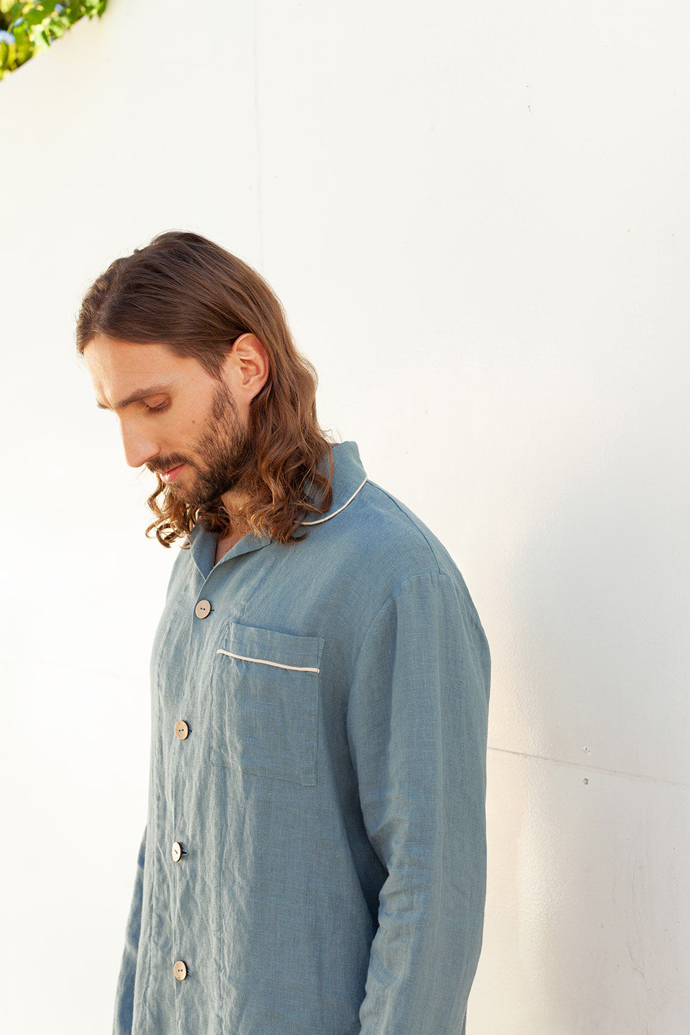 A man wearing a blue linen pajama set with a collar, buttons, and a pocket